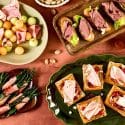A grid collage featuring four festive holiday appetizer dishes, including roasted potatoes, pinwheels, rolled meats, and sliced bread appetizers.